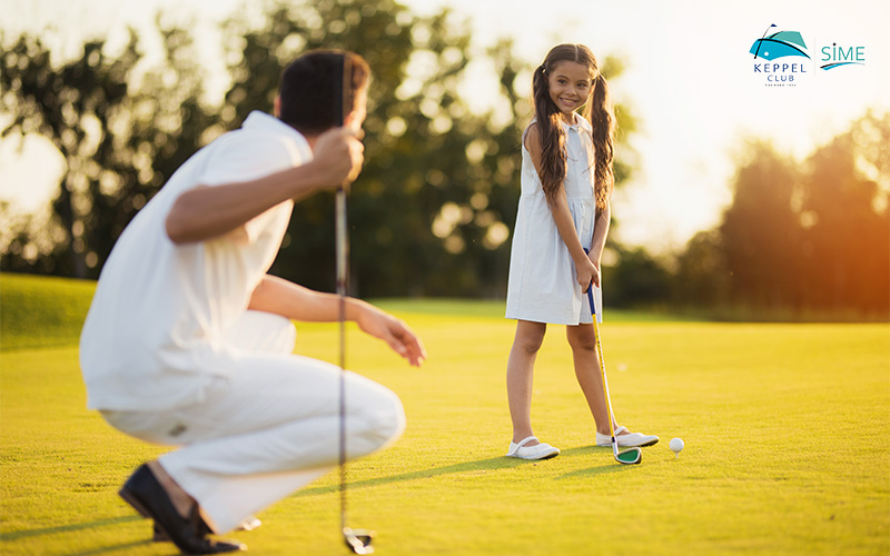 A young kid and his dad playing golf